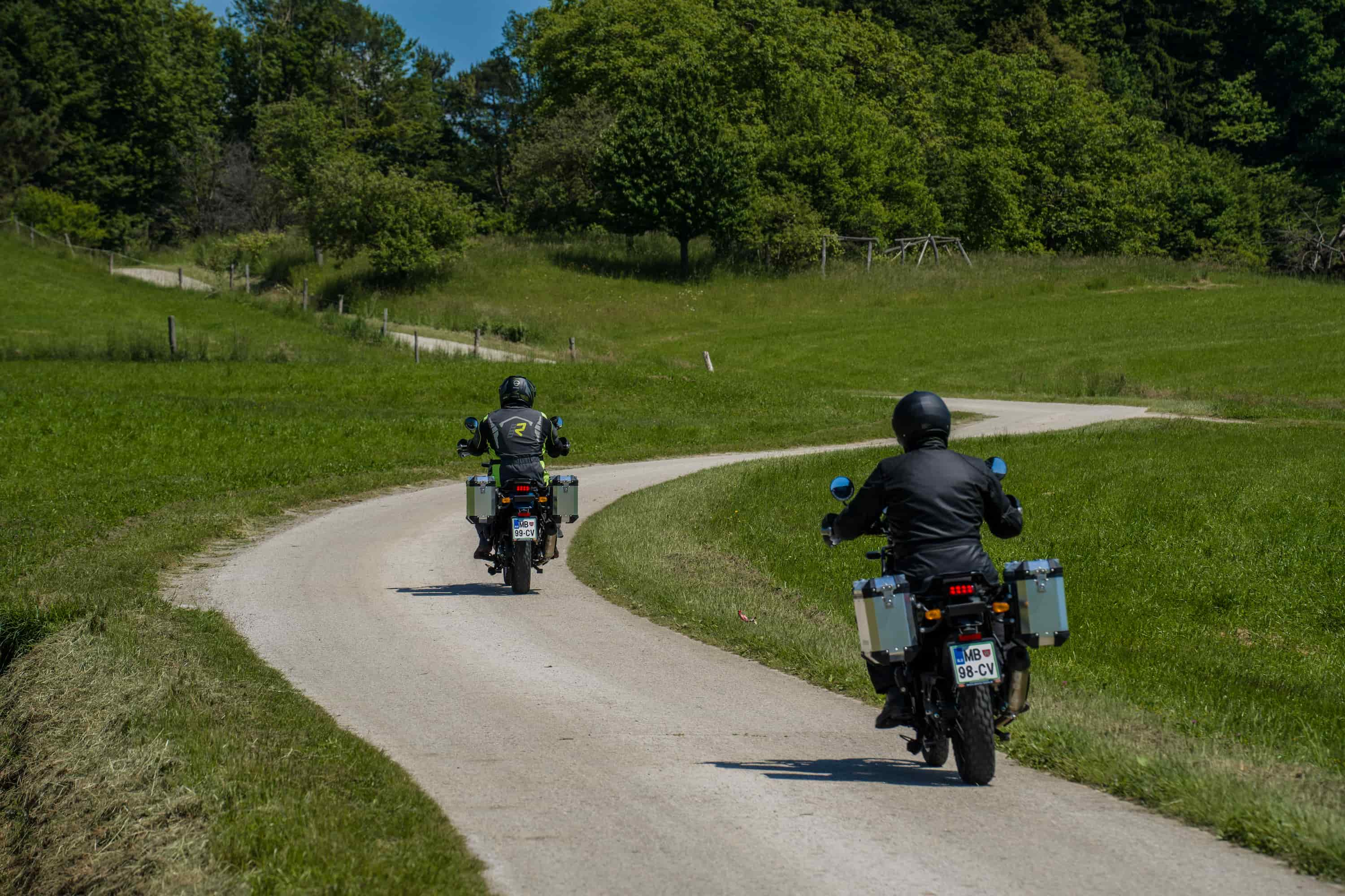 2 men driving royal enfield motorcycles down a country road into the distance