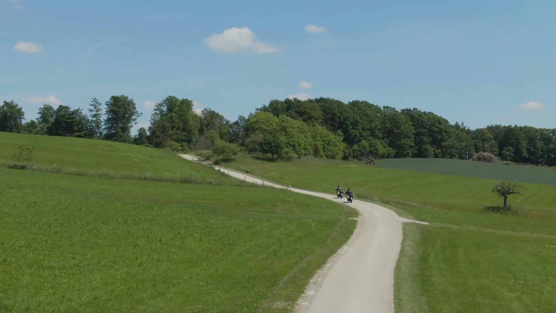 Men riding Royal enfield motorcycles down a country path